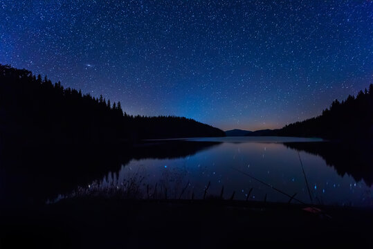 Long time exposure night landscape with starry sky above a mountain lake, Beglik dam in Rhodopi Mountains, Bulgaria