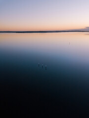 Aerial view of three poles in the middle of lake at dawn.