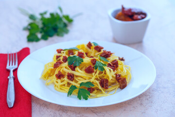 spaghetti with sun-dried red tomatoes and parsley on wooden background