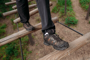 Rope park. A woman in trekking shoes runs a route in a rope park. Close-up of legs