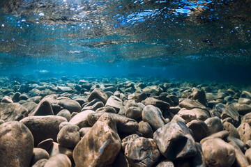 Underwater view with stones and blue transparent water.