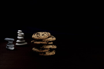 Front view of Zen Pile of chocolate cookies with a stones pile in the back and dark background