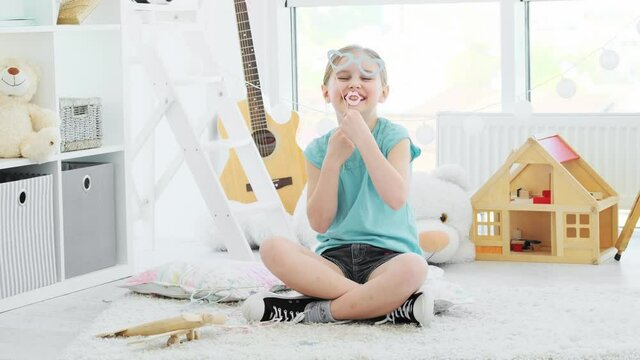 Cute little girl playing with lips and glasses on stick indoors
