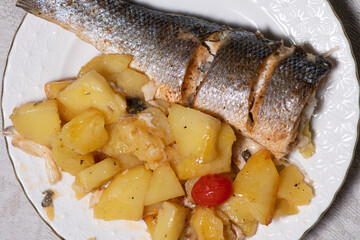 Sea bass fish tail served with potato on a plate