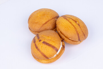 fresh sponge cookies with white cream filling, poured with chocolate, on a white background