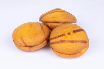 fresh sponge cookies with white cream filling, poured with chocolate, on a white background