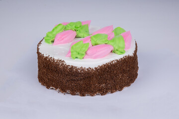 delicious sponge cake with pink and white icing, decorated with cream petals on a white background