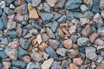 Background with gravel of cranite stones, mostly red granite. Background with stones and rare plant sprouts.