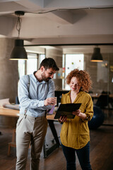 Colleagues in office. Businesswoman and businessman discussing work in office. Two friends in...