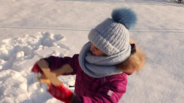 Cute girl with a toy wooden airplane in hand in winter