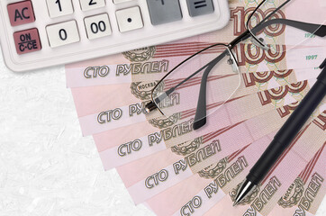 100 russian rubles bills fan and calculator with glasses and pen. Business loan or tax payment...