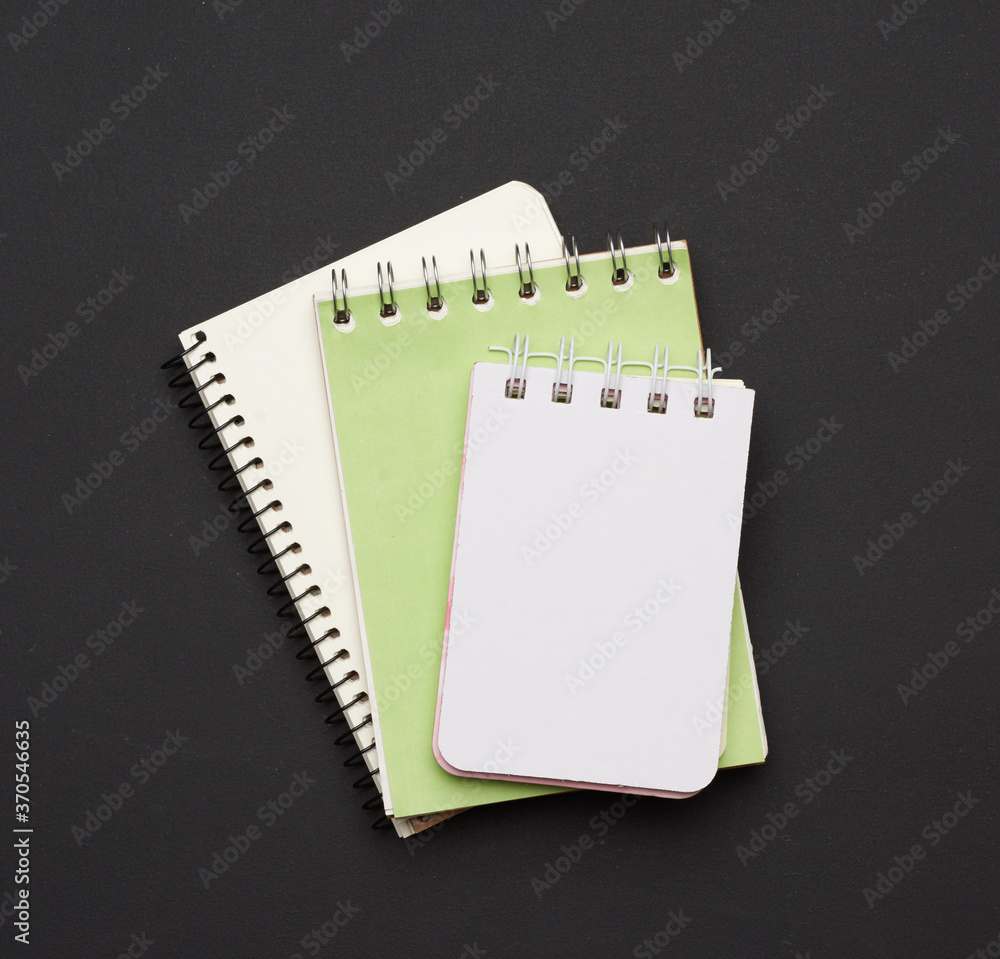 Poster stack of spiral open notebooks with blank white sheets on a black background