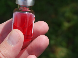 red bottle with medicine in hand on a Sunny day