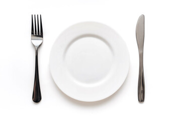 Plate, fork and knife lie on a white tablecloth. The concept of minimalistic table setting, top view.