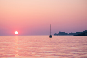 Samotny jacht na tle zachodu słońca na spokojnym morzu