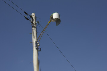 It is a pole and a street light on the background of the blue sky.