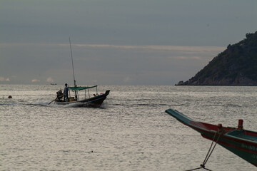sunset on a beach with longtail boat movements in Koh Tao island, Thailand