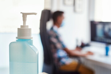 hand sanitizer and man wearing a mask at work