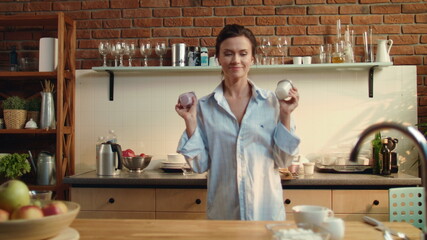 Woman preparing healthy breakfast. Girl putting two yogurt cups on wooden table.