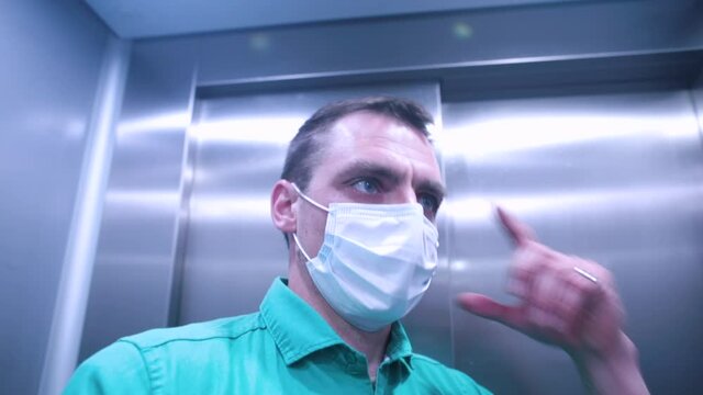 A masked man makes a video call from the elevator. High quA masked man makes a video call from the elevator. Communication of people in the context of the COVID-19 pandemic.ality FullHD footage