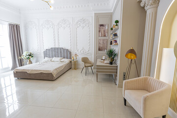 chic luxury interior in an old antique style open-plan apartment decorated with columns and stucco on the wall in pastel colors. tiles on the floor. beige walls