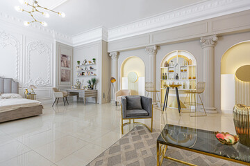 chic luxury interior in an old antique style open-plan apartment decorated with columns and stucco on the wall in pastel colors. tiles on the floor. beige walls