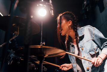 Plays drums. Young beautiful female performer rehearsing in a recording studio