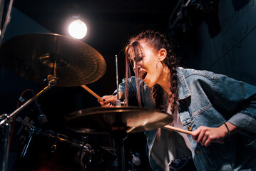 Plays drums. Young beautiful female performer rehearsing in a recording studio