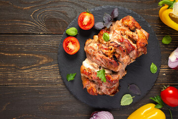 Baked pork ham on a wooden background, fried piece of meat with spices, fresh vegetables, top view