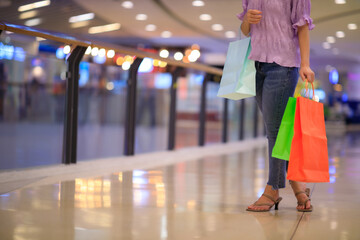 Naklejka premium Women carrying a lot of colorful shopping bags in blurred shopping mall