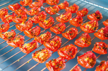 Slices of sun-dried tomatoes on a wire rack in the oven. Close-up, macro