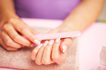 Close up image of woman using nail buffer when doing manicure, polishing nails at home.