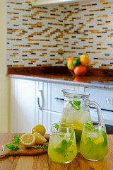 Vintage jug with two glasses of refreshing non alcoholic mojito lemonade drink with lemon slices,...