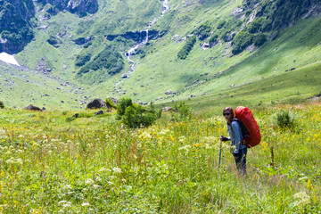 Hiker and backpacker in the mountain valley and field, trekking and hiking scene in Svaneti, Georgia