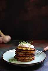 Zucchini fritters, low calorie diet vegetarian zucchini pancakes served with Greek yogurt and lentil sprouts. Dark background, close-up, vertical