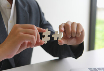 A man uses both hands to try to connect the two jigsaw puzzles together. symbol of association and connection. support and help concept.