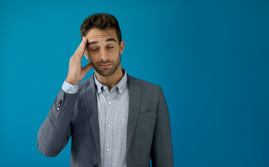 Young businessman looking stressed in front of a blue background