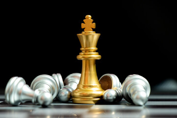 Gold king chess piece win over lying down pawn on black background (Concept for leadership, crisis management)