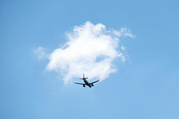 From below of aircraft flying with blue and cloudy sky