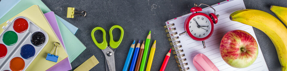 Back to school concept. Flatlay on dark blackboard background with various school office supplies and stationery, top view copy space