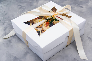 Present box full of fruit cupcakes. Holidays cupcakes with strawberry and blueberry. Cupcake packaging. Delivery.