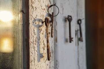 Old rusty key on the wooden door frame with broken white paint with a blurred reflection of a sunset on a dirty glass