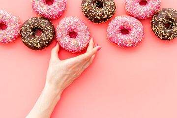 Hand holding donut with icing and sprinkles. Flat lay, top view