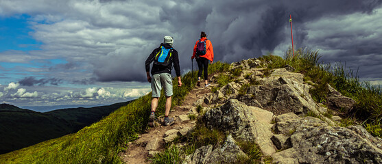 Obraz premium Couple hiking in the mountains. Hiking path in Bieszczady Poland. Rock and stones on hiking trail.