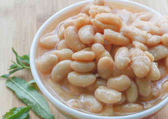 white beans in a plate with mint leaves on a wooden board 