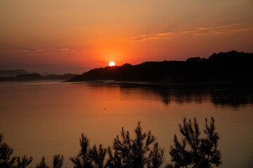 Fototapeta na wymiar Beautiful orange sunset in the river to the sea
