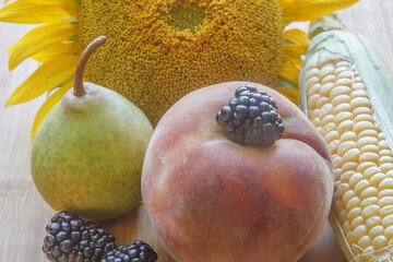 peach, pear, blackberry, corn and sunflower on wood board                                                                                                                                               