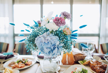 Blue bouquet of fresh flowers on a festive table for dinner. Romantic decor of tables in the restaurant