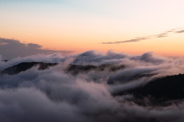 clouds and fog in the evening covering a spectacular mountain landscape. back lighting.
