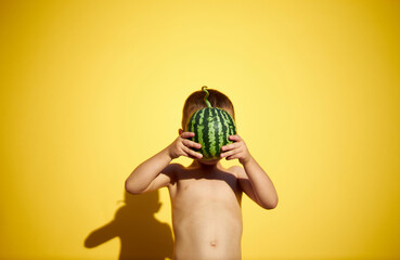 Boy holding a small water melon in hands